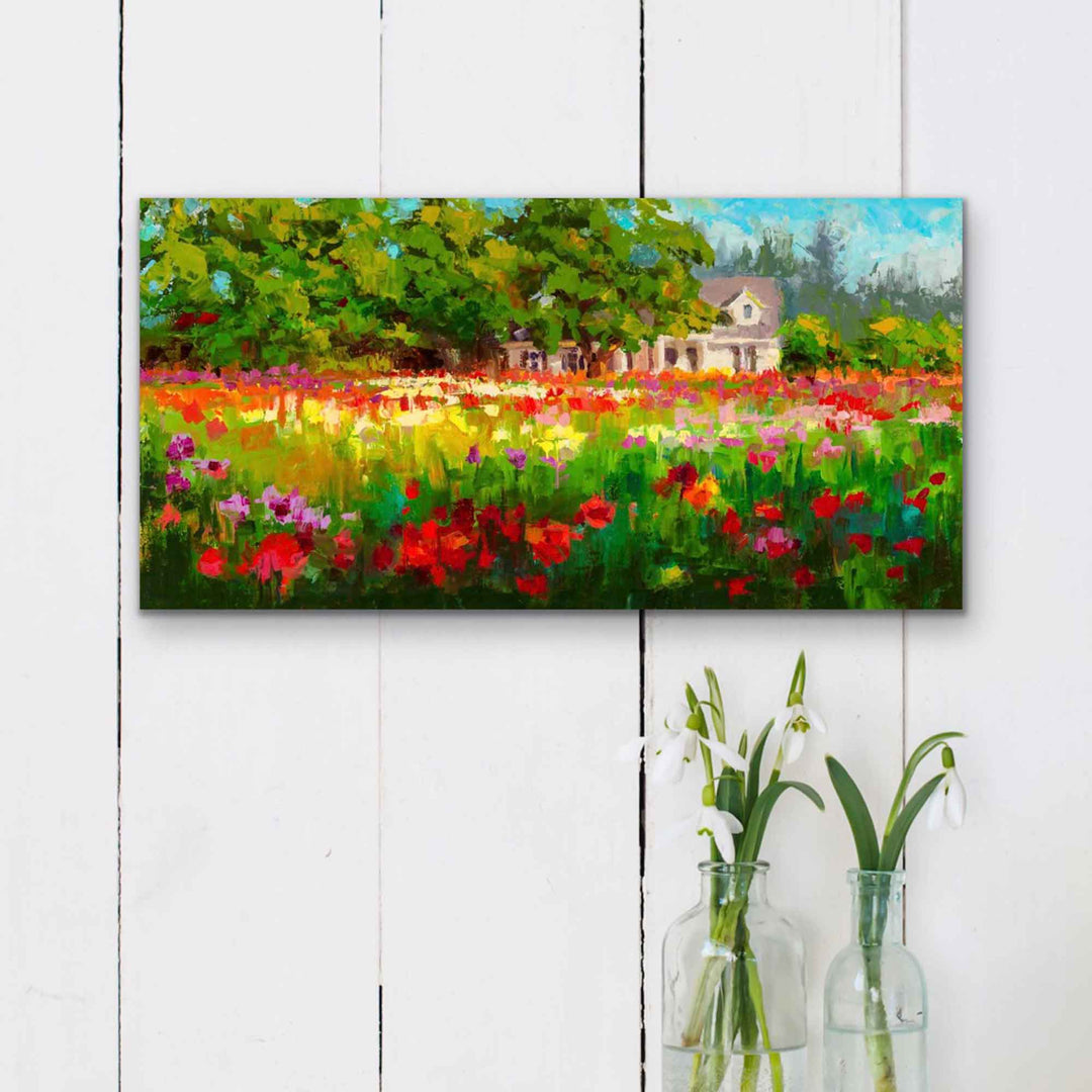 Impressionist canvas art print of a white farmhouse and trees behind a field of colorful dahlias in the afternoon light. The artwork hangs on a shiplap wall with vases of white flowers below.