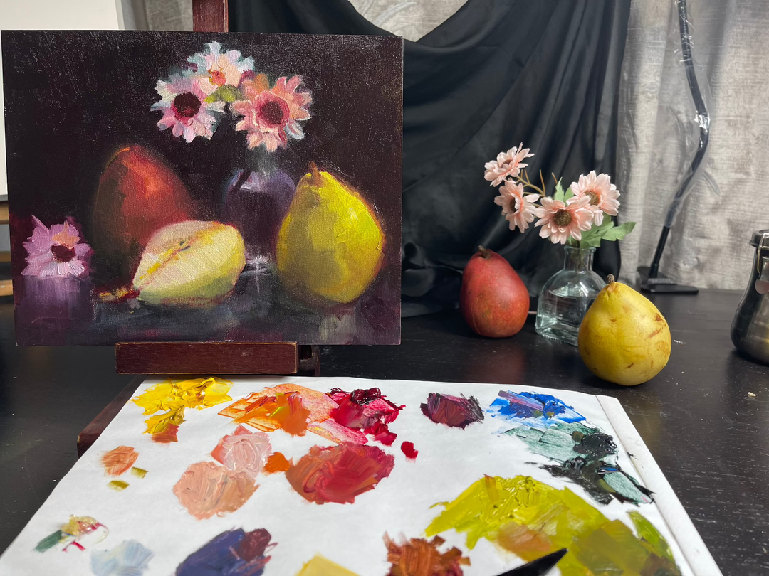 A still life and an oil painting on an easel of the still life with pears and flowers along with oil painting palette