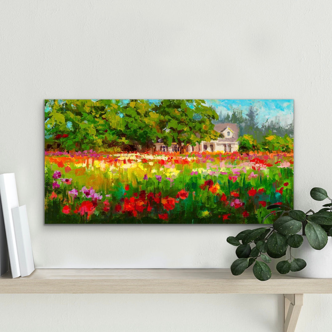Impressionist canvas art print of a white farmhouse and trees behind a field of colorful dahlias in the afternoon light. The artwork hangs above a shelf with book and plant placed on either side.