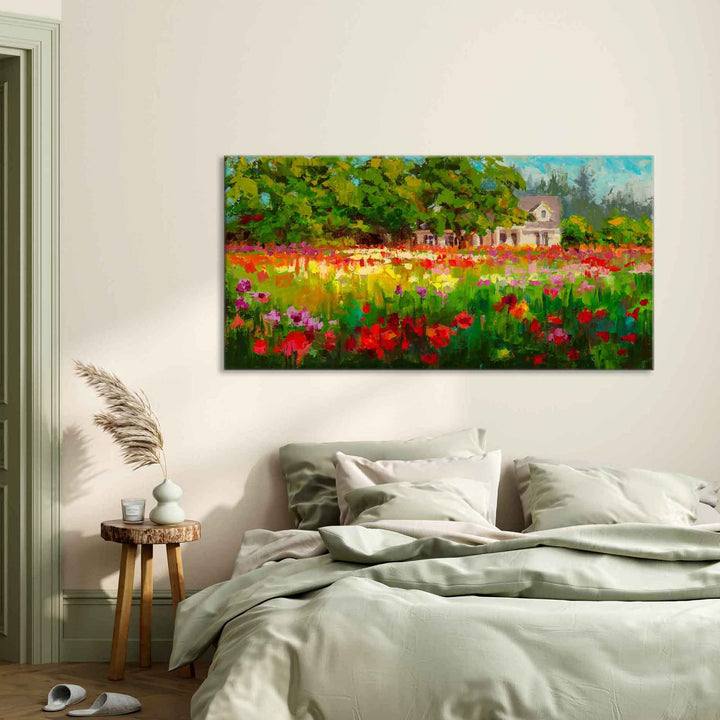 Impressionist canvas art print of a white farmhouse and trees behind a field of colorful dahlias in the afternoon light. The large giclee canvas print hangs on a minimalist bedroom wall with comfortable furnishing and bedding in soft sage greens.